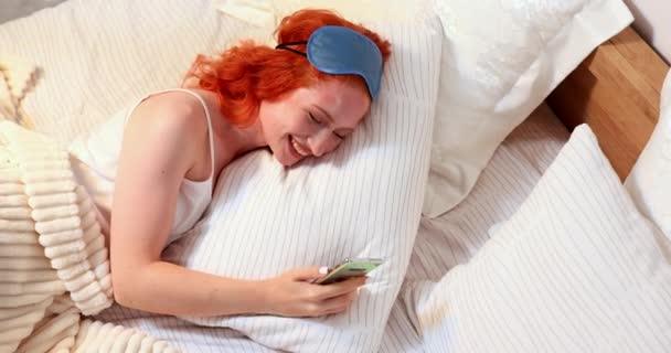 Молода Усміхнена Жінка Використовує Смартфон Обміну Соціальними Медіа Лежачи Ліжку — стокове відео