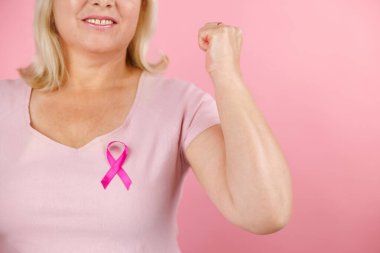 Kadın sağlık kontrolü farkındalığı. Pembe kurdele tutan güzel bir genç kadının portresi göğüs kanseri sembolü, onkoloji hastalarının desteği. Stüdyo çekimi pembe arka planda. Yüksek kalite fotoğraf