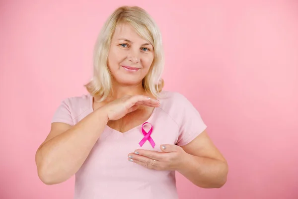 Happy Woman show pink ribbon, great for prevention breast cancer concept. Everything pink, the background, the ribbon and the shirt. High quality photo