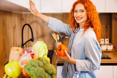 Önlüklü neşeli beyaz kadın mutfakta salata yıkıyor. Ev yemeği konsepti. Yüksek kalite fotoğraf