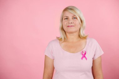 Woman does self-exam for breast cancer prevention wearing pink t-shirt and color background. High quality photo