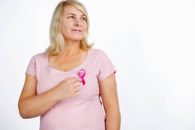 Kanserli kurdele tutan güzel bir kadın mutlu bir yüzü olan, kendine güvenen bir gülümseme ile izole edilmiş beyaz arka planda duruyor. Yüksek kalite fotoğraf