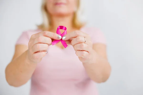 Woman in pink sweater with pink ribbon supporting breast cancer awareness campaign. High quality photo