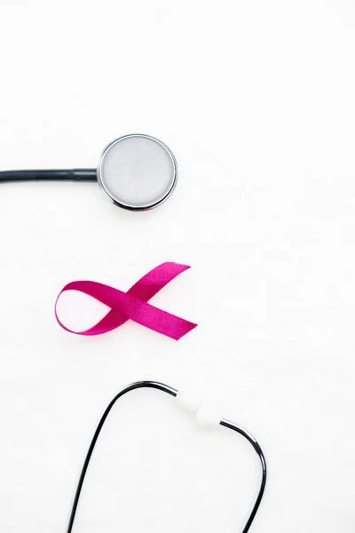 Pink cancer ribbon from satin ribbon isolated on white background with stethoscope. High quality photo