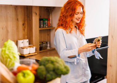 Sağlıklı sebzelerden lezzetli bir yemek yapıyorum. Mutfakta genç bir kadın var. Mutfak kadını ayakta durup salata hazırlarken mutlu mesut gülümsüyor. Yüksek kalite fotoğraf