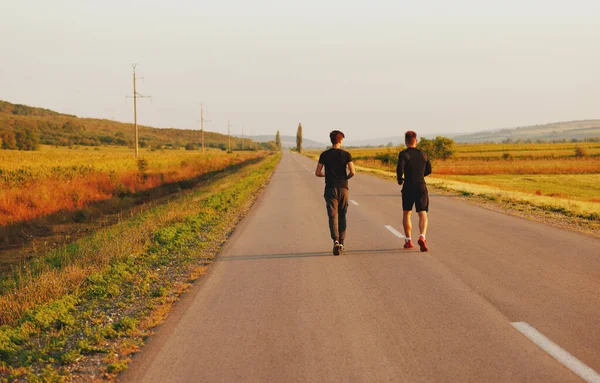 stock image The two sportsmen running on the street. They look very nice in black sports suits. High quality photo