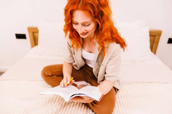 Evde Oturup Yatakta Oturmuş Dergi Okuyan Mutlu Turuncu Saçlı Genç — Stok fotoğraf