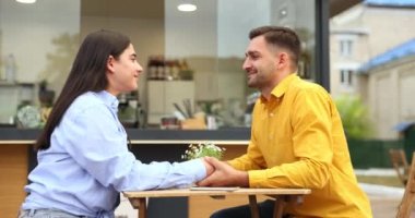 Kafenin önünde sevimli bir çift var. Sarı gömlekli adam karısını öpüyor. Yüksek kalite 4k görüntü