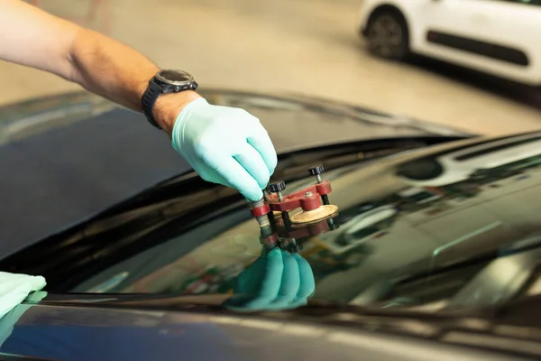 Mechanic using repairing equipment to fix damaged windshield, windshield repairing,. High quality photo