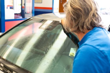 Otomotiv personeli arabanın arka camını mikrofiber bezle temizliyor. Araba temizleme ve vale konsepti. Yüksek kalite fotoğraf