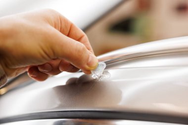 Bir insan, el hareketini kullanarak bir motorlu aracın alaşımlı tekerine etiket yapıştırıyor. Otomotiv lastiği son rötuşun bir parçası olarak parlıyor.