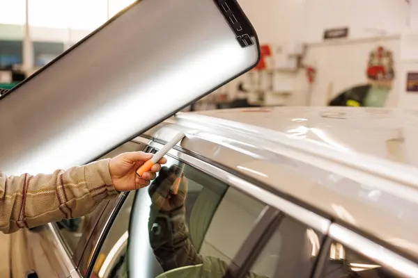 Garajda çalışan bir adam dolu sonrası arabanın olası hasarını kontrol ediyor. Yüksek kalite fotoğraf