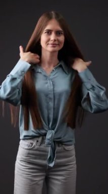 Uzun saçlı, mavi tişörtlü bir kadın, Brezilya usulü saçlarını yaptırdıktan sonra fotoğraf çekimi için farklı şekillerde poz veriyor. Yüksek kalite 4k görüntü