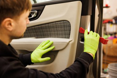 A person in green gloves is cleaning the interior of a vehicle door, showcasing attention to detail in automotive design and maintenance clipart