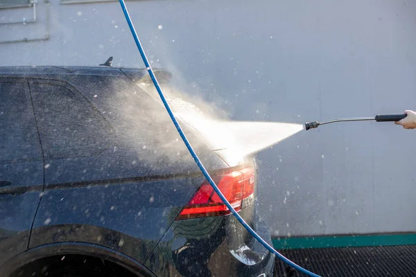 Car washing with high pressure water jet at self service car wash.