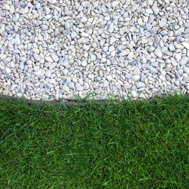 The lawn and pebbles are separated by a border tape