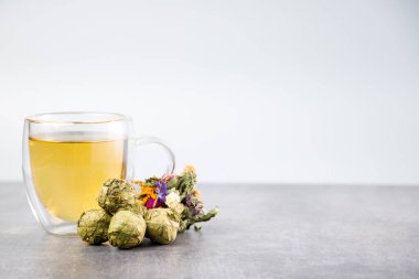 Bir fincan çay ve bitkisel ilaç yakın planda.