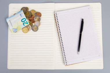 Gri arka planda para ve kalemle dolu bir defter. İş konsepti.