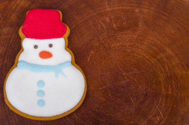 Tahta arka planda fotokopi alanı olan kardan adam kurabiyesi. Üst görünüm.