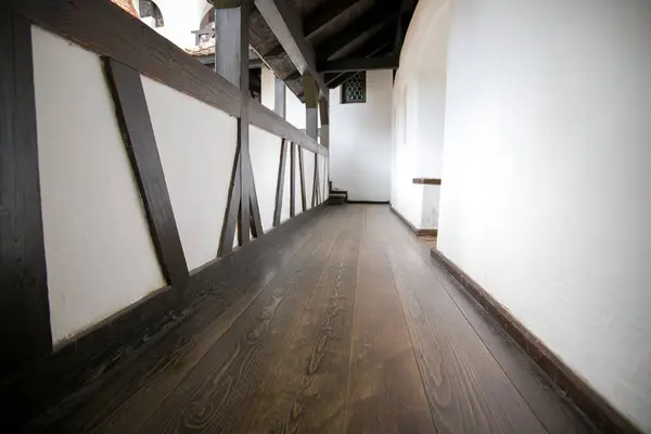 Interior of a wooden house with white walls and wooden floor.