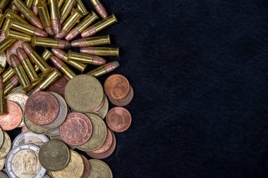 a pile of gold coins and a bullet on black. Copy space. clipart