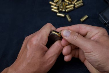 Adamın elleri şarjöre mermi dolduruyor. Travmatik silahlar için fişekler, plastik mermiler..
