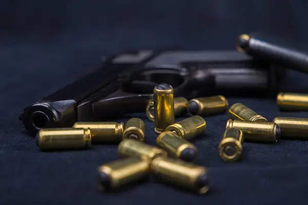 stock image Small-sized self-loading pistol and cartridges for it on a dark background.