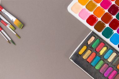 suluboya boya fırçalar ve gri arka planda boya kalemleri.