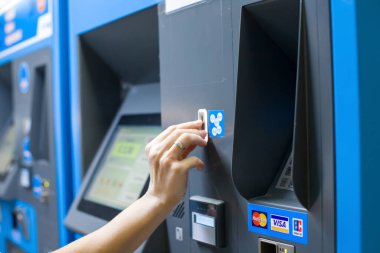 Bir kadın alışveriş merkezinde otomatik vezne makinesiyle park ücretini öder, manzarayı kapat