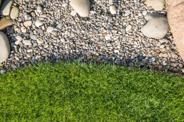 Güneşli bir günde bahçede yeşil çimenler ve çakıl taşları