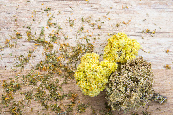 Сушёные букеты бессмертных цветов и яровых цветов на деревянном фоне, травяная медицина. Вид сверху.