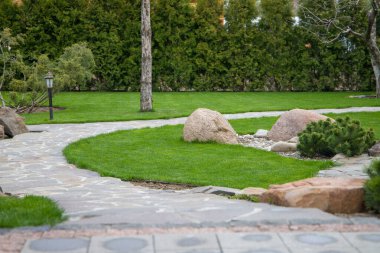 Bahçede yeşil çimenler ve kayalar olan bahçe yolu, manzara tasarımı.