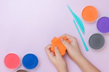 Bir çocuk elinde yumuşak plastisin tutar. Uzayı kopyala Çok renkli plastiksi.