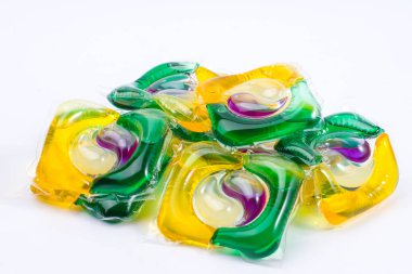 Sarı, yeşil, mor ve beyaz renkli çamaşır jeli kapsülleri yığını.