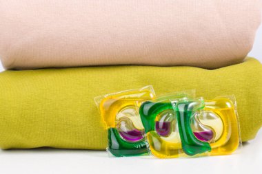 Renkli çamaşır yıkamak için renkli elbise ve jel kapsülleri yığını.