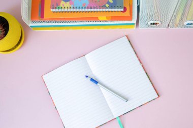 Pembe arka planda defter ve kırtasiye malzemeleri. Okul konseptine dönelim..