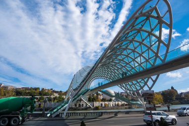 Tiflis, GEORGIA: 05 - 10 - 2022: Barış Köprüsü, Gürcistan 'ın eski Tiflis kentindeki Kura Nehri üzerindeki modern yay şeklinde yaya köprüsü.
