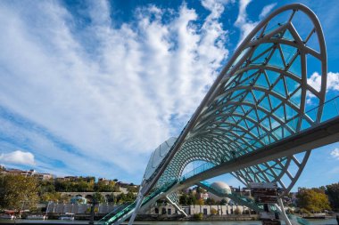 Tiflis, GEORGIA: 05 - 10 - 2022: Barış Köprüsü, Gürcistan 'ın eski Tiflis kentindeki Kura Nehri üzerindeki modern yay şeklinde yaya köprüsü.