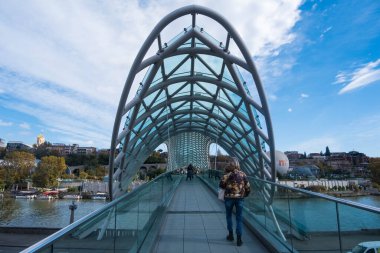 Tiflis, GEORGIA: 05 - 10 - 2022: Barış Köprüsü, Gürcistan 'ın eski Tiflis kentindeki Kura Nehri üzerindeki modern yay şeklinde yaya köprüsü.