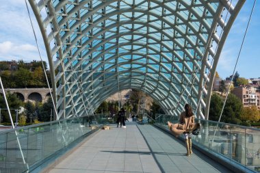 Tiflis, GEORGIA: 05 - 10 - 2022: Barış Köprüsü, Gürcistan 'ın eski Tiflis kentindeki Kura Nehri üzerindeki modern yay şeklinde yaya köprüsü.
