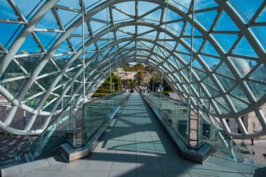 Tiflis, GEORGIA: 05 - 10 - 2022: Barış Köprüsü, Gürcistan 'ın eski Tiflis kentindeki Kura Nehri üzerindeki modern yay şeklinde yaya köprüsü.