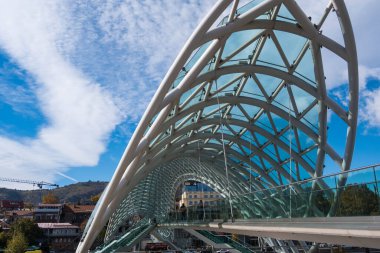 Tiflis, GEORGIA: 05 - 10 - 2022: Barış Köprüsü, Gürcistan 'ın eski Tiflis kentindeki Kura Nehri üzerindeki modern yay şeklinde yaya köprüsü.