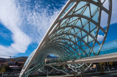 Tiflis, GEORGIA: 05 - 10 - 2022: Barış Köprüsü, Gürcistan 'ın eski Tiflis kentindeki Kura Nehri üzerindeki modern yay şeklinde yaya köprüsü.