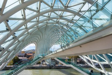 Tiflis, GEORGIA: 05 - 10 - 2022: Barış Köprüsü, Gürcistan 'ın eski Tiflis kentindeki Kura Nehri üzerindeki modern yay şeklinde yaya köprüsü.