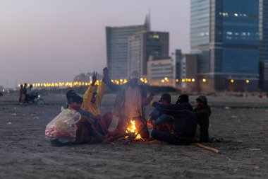 Karachi Pakistan 2021, bir grup balıkçı kışın gün batımından sonra deniz manzarasında balık tutmaya gitmeden önce şenlik ateşi yakıyor..