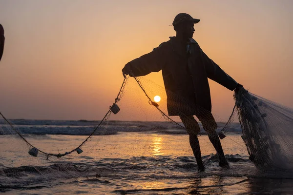 stock image karachi pakistan 2021, a fisherman pulling fishing net to catch fish, at sea view in evening time.