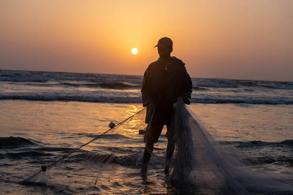 stock image karachi pakistan 2021, a fisherman pulling fishing net to catch fish, at sea view in evening time.