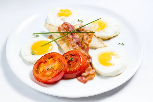 American breakfast with fried eggs, bacon, grilled tomatoes and toast.