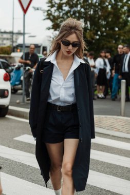 Şort, beyaz çoraplı siyah Prada ayakkabılar ve Milan Moda Haftası Kadın Giyim / Yaz 2024 boyunca PRADA gösterisinin dışında görülen mavi bir ceket giyen bir konuk..