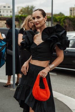 A guest wears earrings, black top and skirt, red fluffy bag, seen outside PRADA show during Milan Fashion Week Womenswear Spring/Summer 2024. clipart